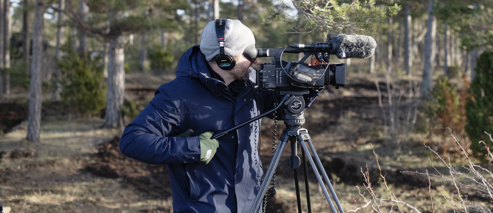 Paul Rhys filming with a Sony camera on a tripod in a pine forest on Gotland